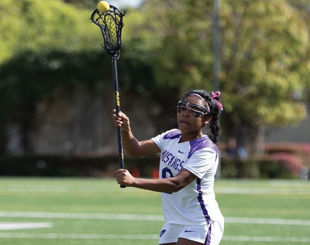 Sophia Cuteño passes a lacrosee ball in a Varsity lacrosse match